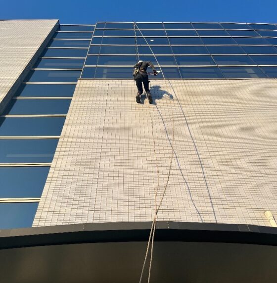 ブランコ工法で建物のタイル外壁を打診調査している作業員